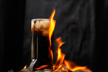 Glass cup with cola and ice. Fire