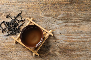 Cup of Da Hong Pao oolong and tea leaves on table, top view with space for text