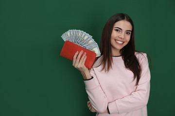 Young woman with money in wallet on color background. Space for text