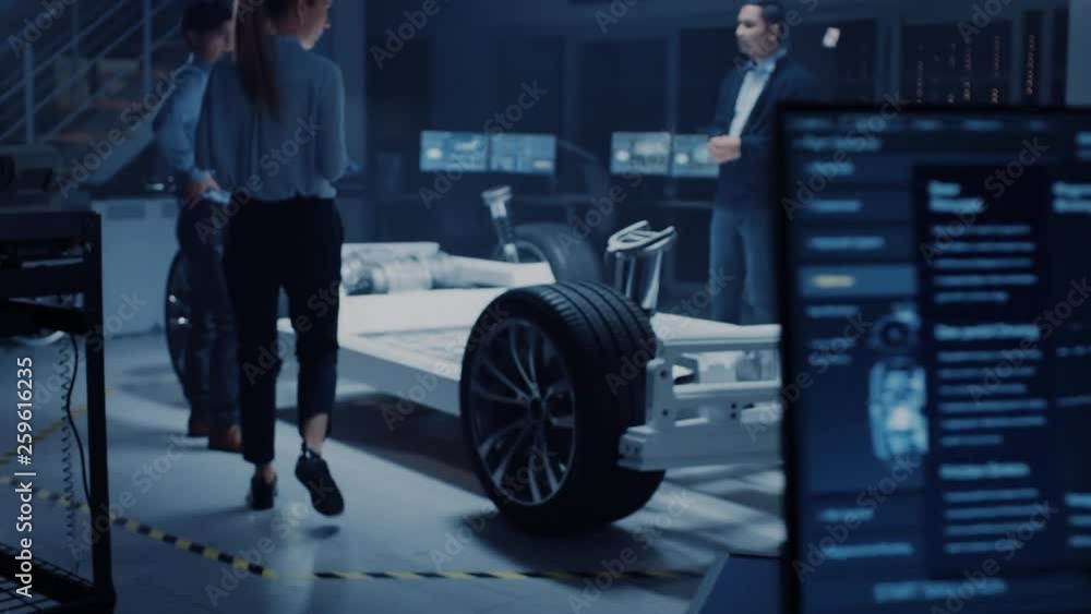 Aufkleber Automotive Design Engineers Talking while Working on Electric Car Chassis Prototype. In Innovation Laboratory Facility Concept Vehicle Frame Includes Wheels, Suspension, Engine and Battery.