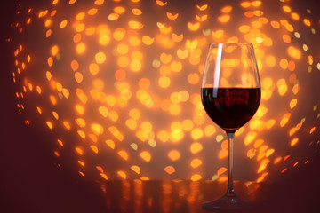 Glass of wine on table against blurred lights. Space for text