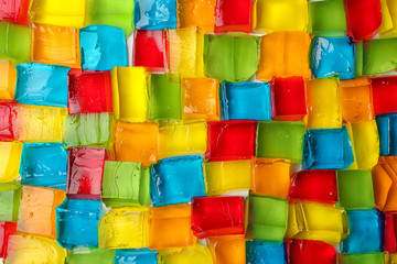 Tasty colorful jelly cubes as background, top view