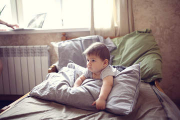 Fototapeta premium funny shaggy baby on bed with pillow, waking up