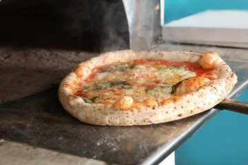 Taking out tasty pizza from oven in restaurant kitchen