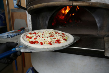 Chef putting tasty pizza into oven in restaurant kitchen
