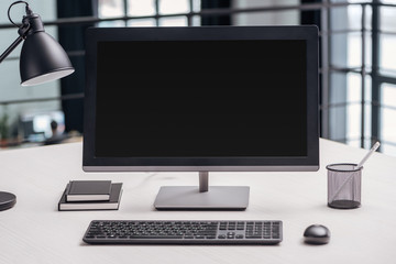 computer monitor with blank screen and stationery at workplace