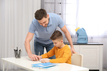 Obraz na płótnie Canvas Dad helping his son with homework in room