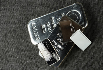 Several different silver bars against the background of the texture of coarse cloth. .