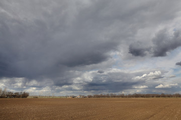 Agriculture, cultivated field with dark clouds in spring