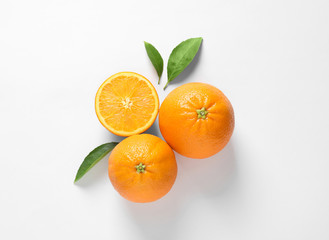 Juicy oranges and leaves on white background, top view