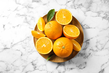Plate with ripe oranges on marble background, top view