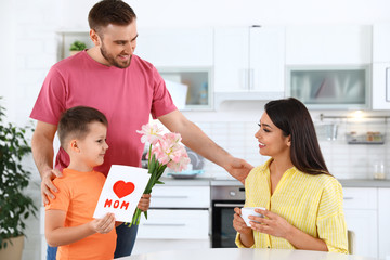 Father and son congratulating mom in kitchen. Happy Mother's Day