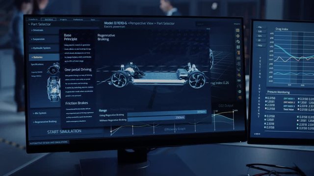 Professional Engineer Works on a Computer with a 3D CAD Software and Tests the Electric Car Chassis Prototype with Wheels, Batteries and Engine Standing in a High Tech Development Laboratory.