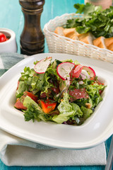 Fresh vegetable salad, radishes, tomatoes, lettuce, dill, blue wooden background