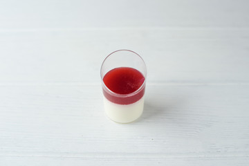 Red and white panacotta in little glasses on white wooden background. Place for text
