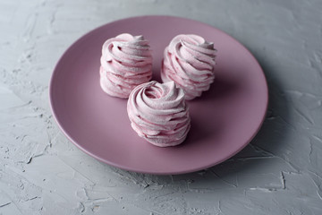 Homemade pink zephyr or marshmallow on pink plate with copy space on grey background. Marshmallow,...