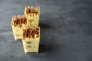 Three small cups of tiramisu dessert on grey background. Place for text