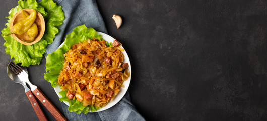 Traditional dish of polish cuisine - Bigos from fresh cabbage, meat and prunes. Top view with copy space.