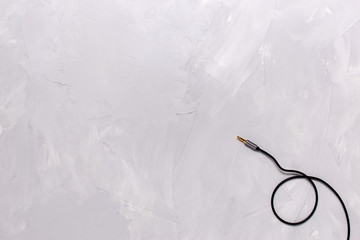 Metal gold plug on a black audio instrument cable, on a plastered background close-up from right to left. Flat lay. Copy Space.