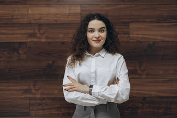 Young happy businesswoman in office with crossed arms