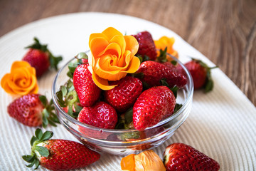 Fresh organic strawberries in a glass bowl on wooden table