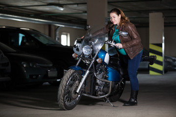 Fototapeta na wymiar Woman trying to sit on motorcycle, standing in dark parking