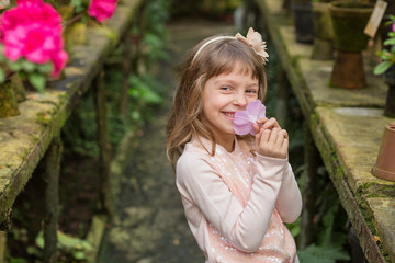 Little girl playing with flowers in greenhouse.