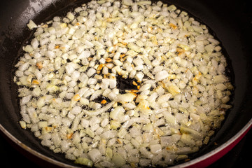 fried onions in a pan in oil, for cooking. Close up