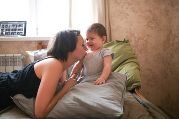 young mother brunette kiss and hugs baby daughter