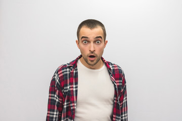 Attractive guy in plaid shirt having opened a mouth from shock, looking at camera, front view, white background with copy space, for advertising