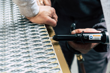 Workers assembling metal frames with rivet gun on the production line