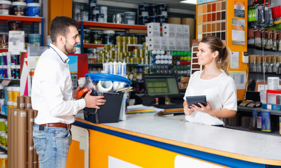 woman seller consulting male customer at the counter in tool-ware shop