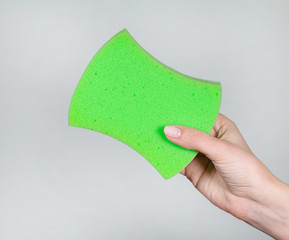 Close up view of new green and white bath sponge in hand of young woman with beautiful pastel pink...