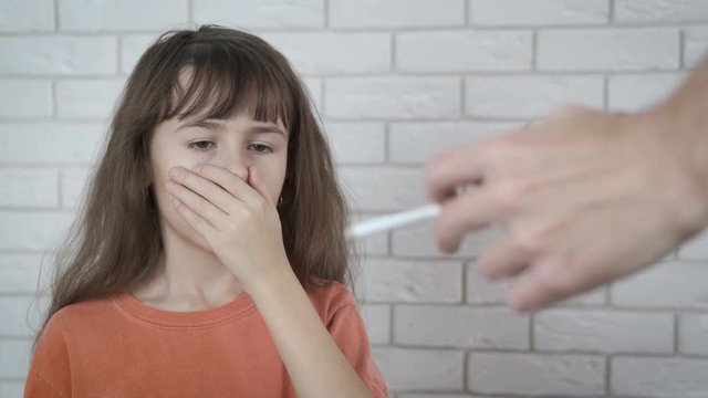 The child is choking on cigarette smoke. Childhood without cigarettes. The little girl is choking on the cigarette smoke.