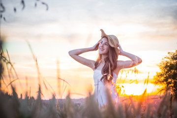Portrait of young beautiful girl in the white dress with hat in wheat field, walking, carefree....