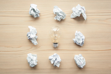 Many crumpled white paper balls with one light bulb between them. Concept of think different, think out of the box, leadership.