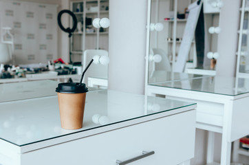 A cup of coffee on dressing table near mirror in makeup room