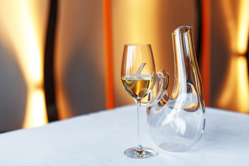 glass of wine and a decanter on a table with a white tablecloth.