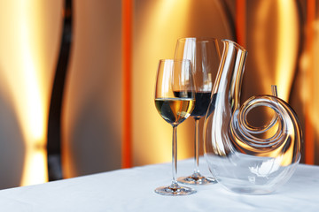 glass of wine and a decanter on a table with a white tablecloth.