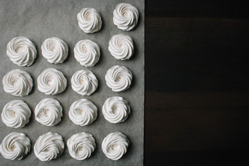 The process of making marshmallow. Close up hands of the chef with confectionery bag cream to parchment paper at pastry shop kitchen. The recipe for making marshmallow. Copy space