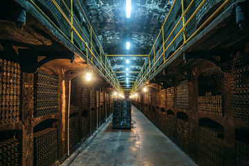 Wine cellar with many dusty bottles of alcohol, underground warehouse for fermentation and wine storage