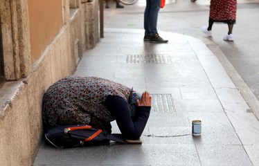 gypsy woman asking for alms kneeling on the ground with her hand