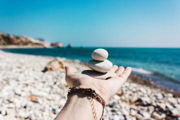 Fototapeta na wymiar Balance of stones on the hand against the background of the sea.