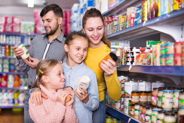 Fototapeta na wymiar Parents with daughters choosing fresh products in food store