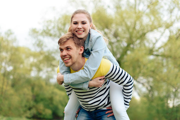Fototapeta premium young beautiful girl on the back of a young man outdoors in summer 1