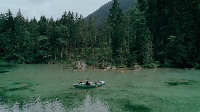 Aerial drone footage of idyllic and peaceful tranquil scene of young happy family on getaway weekend date or holiday, row boat on clean and pristine lake in mountains. concept nature tourism activity
