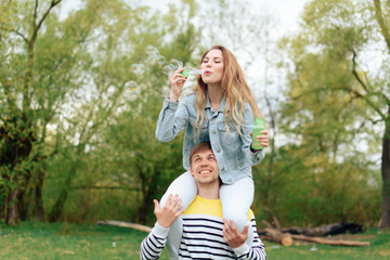 Obraz premium young beautiful girl on the back of a young man outdoors in summer 1