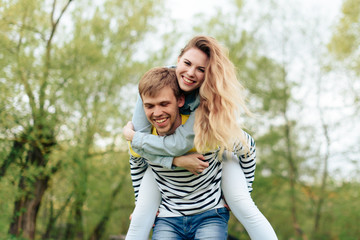 young beautiful girl on the back of a young man outdoors in summer 1