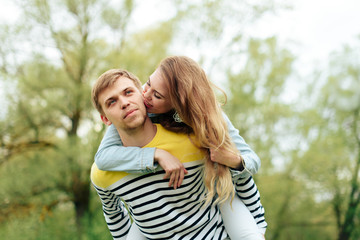 Fototapeta premium young beautiful girl on the back of a young man outdoors in summer 1