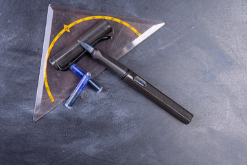 Fountain pen with ink cartridges and geo-triangle on a board copy space
